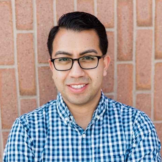 Danny Reyes smiling, wearing glasses and a blue checked shirt